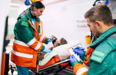 Sağlık görevlileri ambulansta sedyede yatan kıdemli bir hastayla ilgileniyorlar..