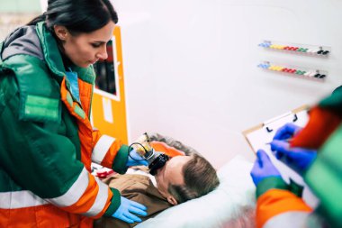 Doktorların acil durumu ya da sağlık görevlileri, yaşlı bir hastayla ambulansta sedyede yatarken birlikte çalışıyorlar..