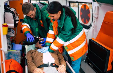 Bilinci kapalı yaşlı adam ve ambulansta çalışan sağlık görevlileri.