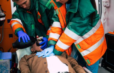 Bilinci kapalı yaşlı adam ve ambulansta çalışan sağlık görevlileri.