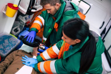 Bilinci kapalı yaşlı adam ve ambulansta çalışan sağlık görevlileri.