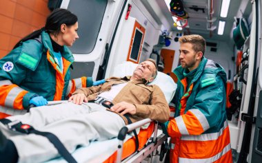 Ambulanstaki ciddi ve profesyonel doktorlar acil bir durum sırasında bir hastayı hastaneye götürüyorlar..