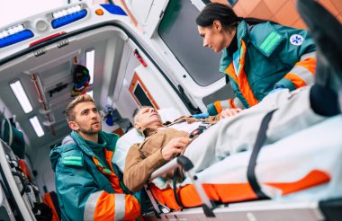 Ambulanstaki ciddi ve profesyonel doktorlar acil bir durum sırasında bir hastayı hastaneye götürüyorlar..