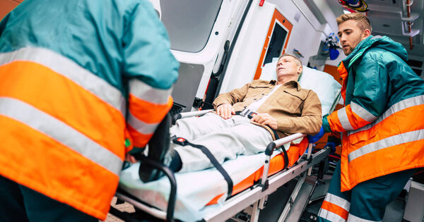 Serious and professional team of doctors in the ambulance moving on a patient into the hospital during an emergency situation.