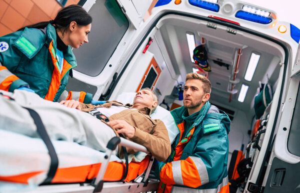 Serious and professional team of doctors in the ambulance moving on a patient into the hospital during an emergency situation.