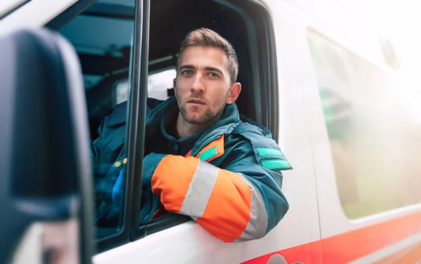 Professionele Zelfverzekerde Jongeman Arts Zoek Naar Camera Met Ambulance Achtergrond — Stockfoto