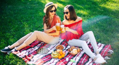 Mutlu gülümseyen güzel şirin ve heyecanlı en iyi arkadaşlar ya da kız kardeşler yaz günü kır evinde piknikte eğleniyorlar.