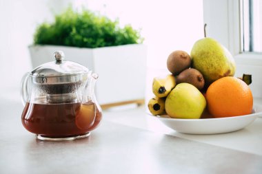 Çay, kahve ve mutfaktaki masada duran meyveli çaydanlık.