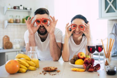 Mutfakta yemek pişiren ve sağlıklı meyve salatası yaparken birlikte eğlenen heyecanlı, genç ve güzel bir çift.
