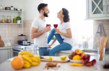 Mutfakta yemek pişiren ve sağlıklı meyve salatası yaparken birlikte eğlenen heyecanlı, genç ve güzel bir çift.