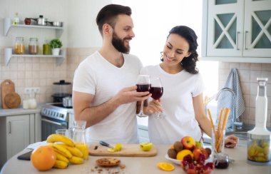 Mutfakta yemek pişiren ve sağlıklı meyve salatası yaparken birlikte eğlenen heyecanlı, genç ve güzel bir çift.