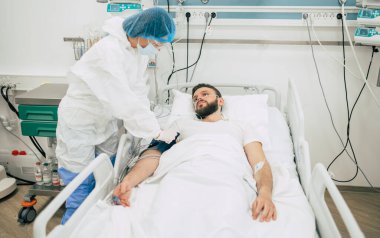 Coronavirus covid-19 hastanedeki bir karantina koğuşunda, onu tedavi ederken koruyucu giysiler giyen doktorlarla birlikte.