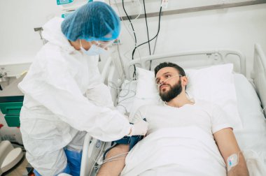 Coronavirus covid-19 hastanedeki bir karantina koğuşunda, onu tedavi ederken koruyucu giysiler giyen doktorlarla birlikte.