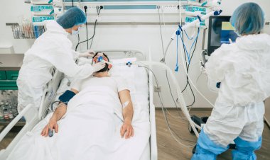 Coronavirus covid-19 hastanedeki bir karantina koğuşunda, onu tedavi ederken koruyucu giysiler giyen doktorlarla birlikte.