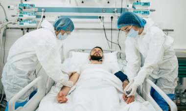 Coronavirus covid-19 hastanedeki bir karantina koğuşunda, onu tedavi ederken koruyucu giysiler giyen doktorlarla birlikte.