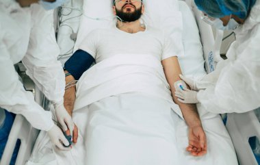 Coronavirus covid-19 hastanedeki bir karantina koğuşunda, onu tedavi ederken koruyucu giysiler giyen doktorlarla birlikte.