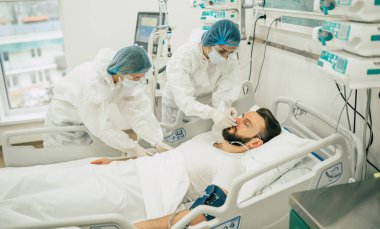 Coronavirus covid-19 hastanedeki bir karantina koğuşunda, onu tedavi ederken koruyucu giysiler giyen doktorlarla birlikte.