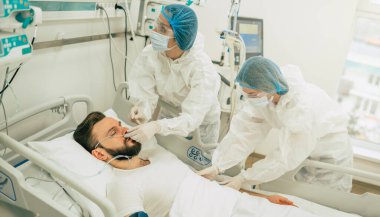 Coronavirus covid-19 hastanedeki bir karantina koğuşunda, onu tedavi ederken koruyucu giysiler giyen doktorlarla birlikte.