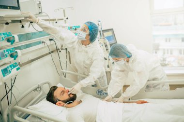 Coronavirus covid-19 hastanedeki bir karantina koğuşunda, onu tedavi ederken koruyucu giysiler giyen doktorlarla birlikte.