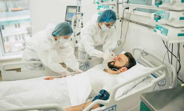 Coronavirus covid-19 hastanedeki bir karantina koğuşunda, onu tedavi ederken koruyucu giysiler giyen doktorlarla birlikte.