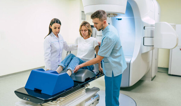 Cancer treatment in a modern medical private clinic or hospital with a linear accelerator. Professional doctors team working while the woman is undergoing radiation therapy for cancer