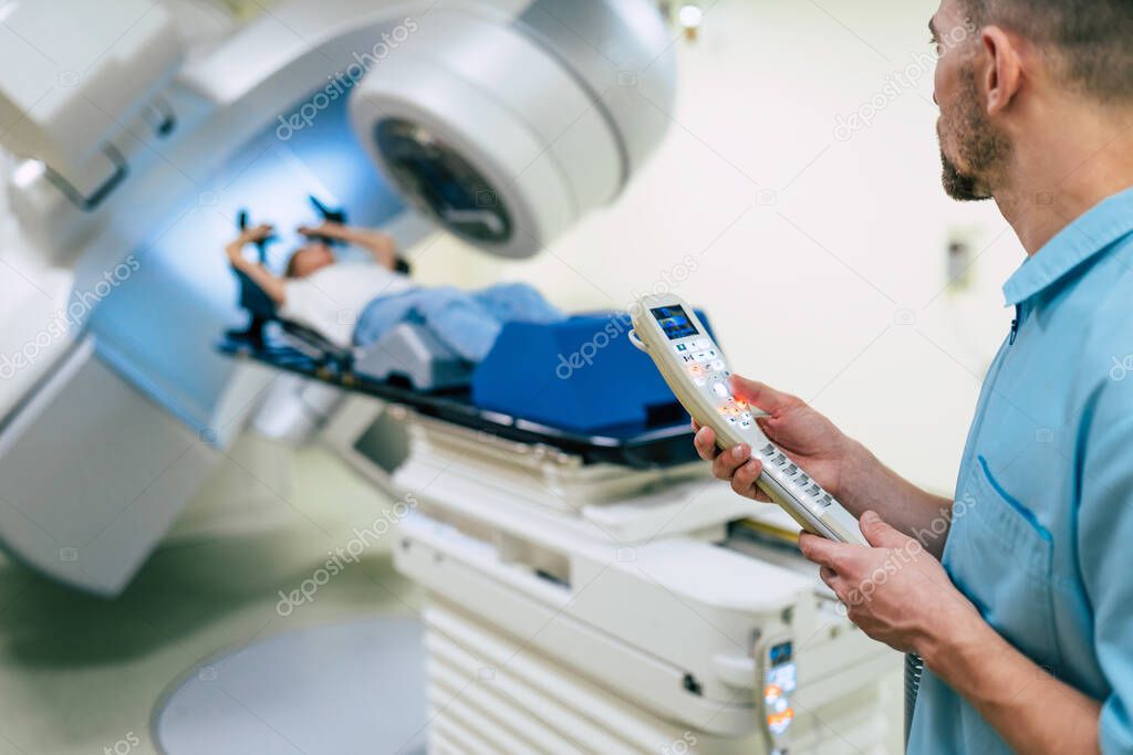 Cancer treatment in a modern medical private clinic or hospital with a linear accelerator. Professional doctors team working while the woman is undergoing radiation therapy for cancer