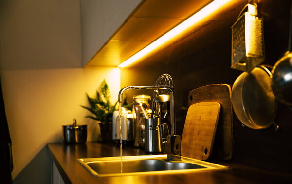 Современная и технологичная кухня в новом роскошном доме с деревянным островом, полами из лиственных пород, шкафами из белого дерева и стальными шкафами. Концепция дизайна и интерьера