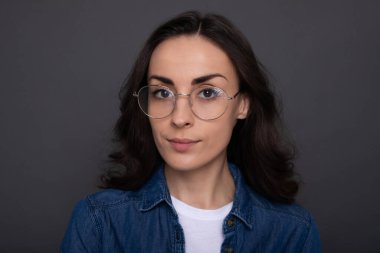 Gri duvarda gözlüklü çekici, esmer bir kadının portresini yakından çek.