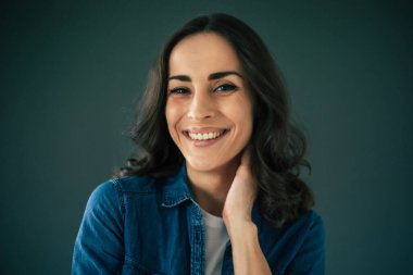 Gri duvarda gülümseyen, çekici, esmer bir kadının portresini yakından çek.