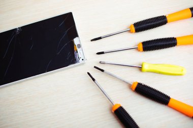 Close up photo of broken or damaged smartphone with professional tools on the table