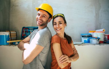 Yeni ev onarımı ya da duvarların yenilenmesi sırasında gündelik giysiler içinde birbirine aşık modern mutlu genç bir çift.
