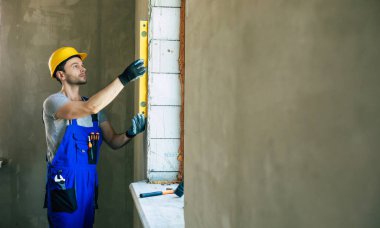 Genç erkek ya da işçi tamirat işiyle meşgul. İnşaat malzemeleri taşıyor. Yeni binada günlük iş kıyafetleri giyiyor.