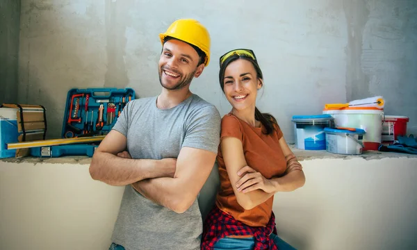 Yeni ev onarımı ya da duvarların yenilenmesi sırasında gündelik giysiler içinde birbirine aşık modern mutlu genç bir çift.