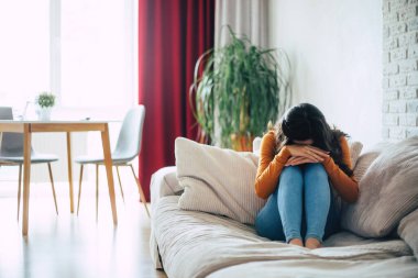 Derin depresyondaki üzgün kadın kanepede oturup ağlıyor ve kötü şeyleri düşünüyor.