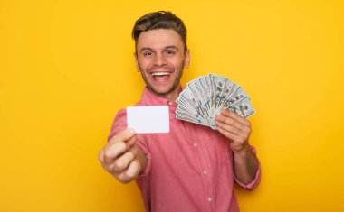 Yakışıklı, başarılı, modern bir adam internette alışveriş yapmak için kredi kartı ve bir sürü para kullanıyor.