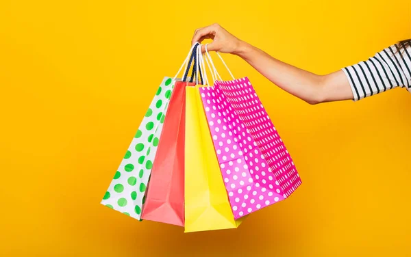 Sarı Arka Planda Izole Edilmiş Renkli Alışveriş Çantasıyla Kadın Elinin — Stok fotoğraf
