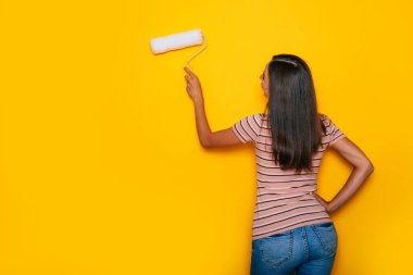 Dairenin yenilenmesi sırasında boya silindirli hoş bir genç kadın.