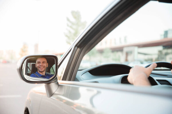 Крупным планом фото молодого красивого успешного мужчины за рулем его современной машины