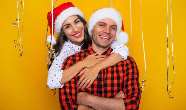 Noel Baba şapkalı, mutlu ve heyecanlı genç bir çiftin birbirine sarılıp Noel ve yeni yılı kutlarken poz verdiği yakın bir fotoğraf.