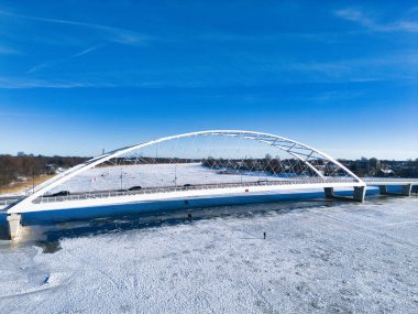 Donmuş Parnu Nehri üzerindeki modern beyaz kemer köprüsünün kışın insansız hava aracı görüntüsü