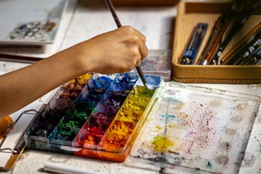 Sanatçı, Rustik Ahşap Masa Yaratıcı Süreci 'nde canlı suluboyaları Renkli Boya Paleti ile Karıştırıyor ve Parlak Suluboya Seti ile El Resimlerini Kapatıyoruz