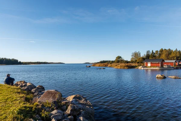 Güneşli bir sonbahar gününde İskandinav çam ormanlarında ahşap bir yolda yürüyen gezgin, mavi gökyüzü, bulutlar ve ılık altın ışıkla huzurlu doğayı keşfediyor.
