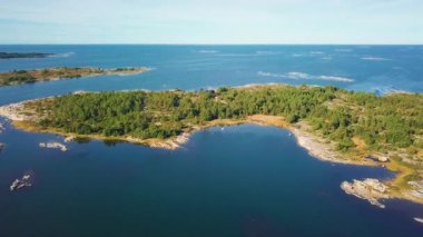 Sonbaharda Finlandiya 'nın kayalık kıyıları, sakin mavi suları ve renkli ormanlarıyla birlikte Baltık takımadaları üzerinde uçan insansız hava aracı görüntüleri. Seyahat, doğa ve manzara teması için ideal