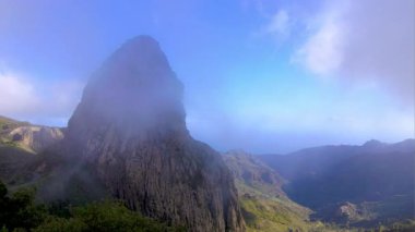 Alçak bulutlar ve sis sarp bir dağın etrafında sürükleniyor. Atmosferik manzara görüntüleri, engebeli araziyi ve dramatik dağlık araziyi gözler önüne sermek için sis berraklığı.