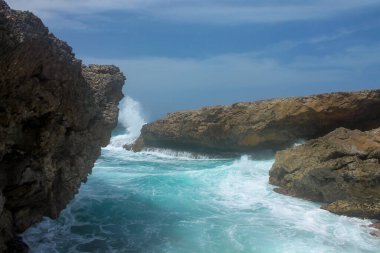 Güneşli bir günde, bir sonraki dalga kayaların arasına dalmadan önce su bir an için sakinleşir.