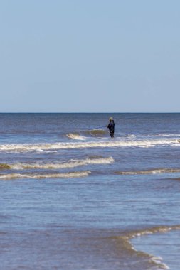 Danimarka 'da bir plajda oltayla balık tutarken tanınmayan bir adam. Sahne, İskandinav ortamında doğa, yalnızlık ve geleneksel balıkçılığın birleştiği huzurlu bir sahil eğlencesi anı yakalıyor.