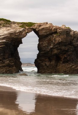 Kuzey İspanya, Galiçya 'daki Katedraller Plajı' ndaki muazzam kaya kemerlerinin çarpıcı görüntüsü. Atlantik Okyanusu tarafından oyulmuş bu doğal kireçtaşı katedralleri, dramatik ölçekte ve engebeli güzelliği gözler önüne serer.