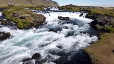 İzlanda doğası. Küçük bir şelalesi olan, nehrin yanında İzlanda yosunu var..