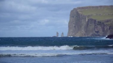 Risin ve Kellingin, Danimarka, Avrupa 'daki Faroe Adaları' ndaki Streymoy 'da dalgaların vurduğu Tjornuvik körfezinden görüldüğü gibi kayalar.