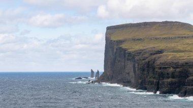 Risin ve Kellingin, Danimarka, Avrupa 'daki Faroe Adaları' ndaki Streymoy 'da dalgaların vurduğu Tjornuvik körfezinden görüldüğü gibi kayalar.